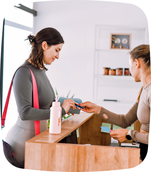 A staff member assists a customer in person, showcasing how TeamUp’s integrated payment system simplifies transactions and creates a smooth, convenient experience—both online and in-studio. This seamless flow is part of TeamUp’s all-in-one platform, trusted by studios as a leading Class Booking System for Yoga.