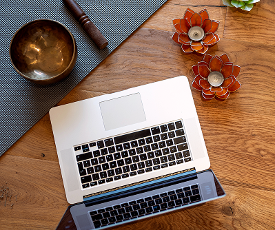 Top-down view of a laptop on a yoga mat beside a singing bowl and candles, symbolizing the blend of wellness and technology. Promotes a resource titled “How to choose the best yoga studio software,” helping studio owners compare and select the right Yoga Studio Management Software for their business.
